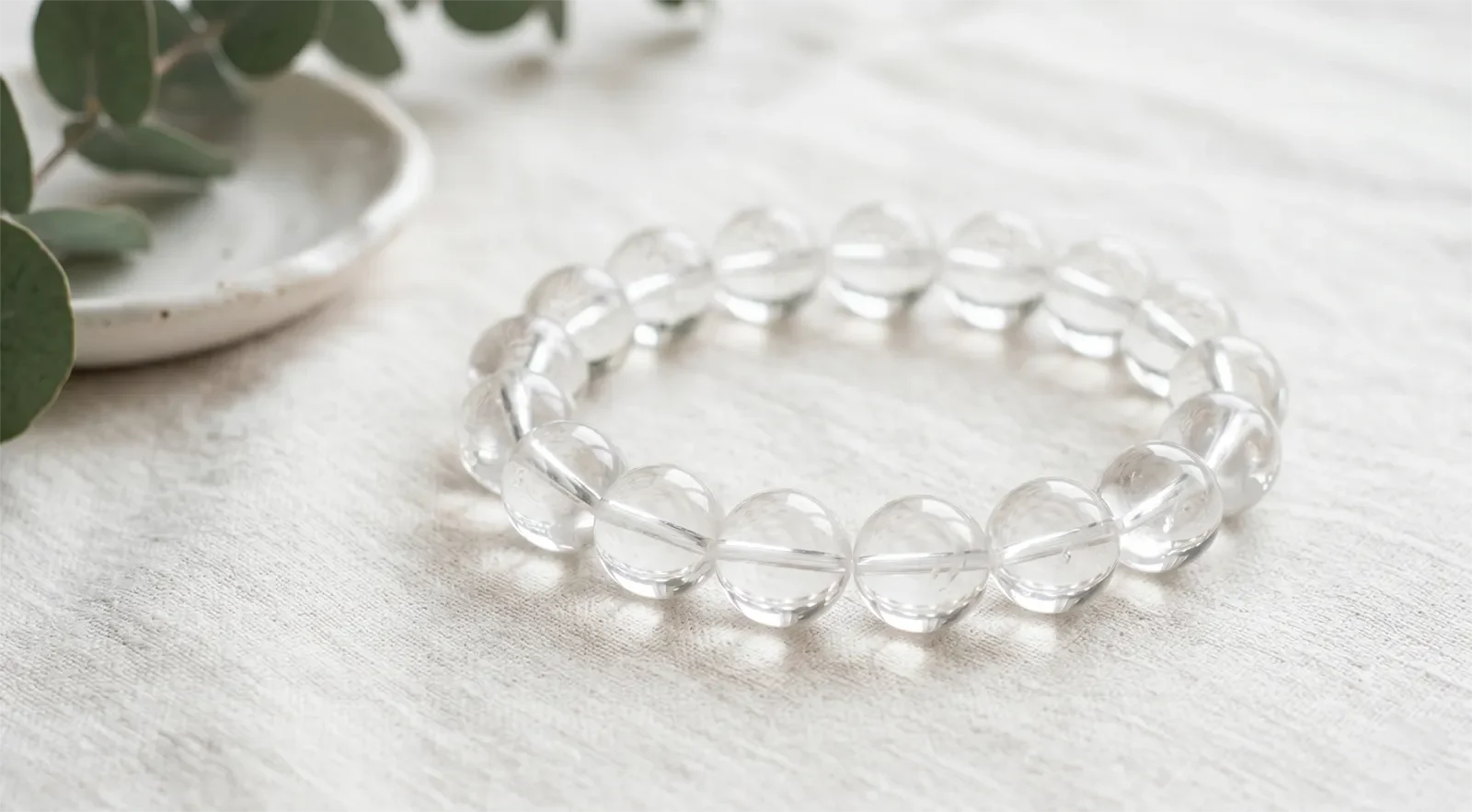 Vòng tay thạch anh trắng hạt lớn đặt trên nền vải màu kem sáng