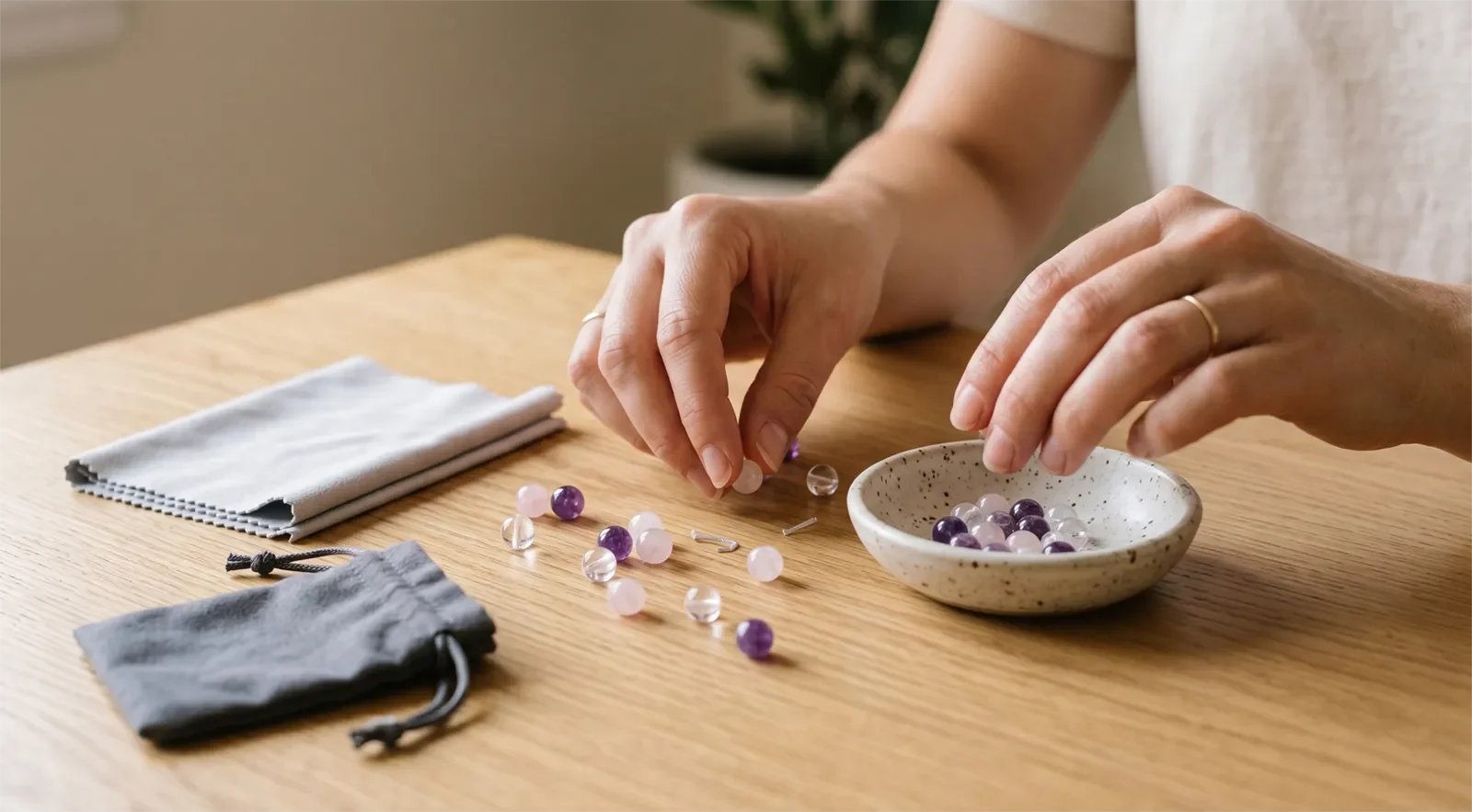 A person gently collecting scattered crystal bracelet beads into a small ceramic dish after a bracelet breaks