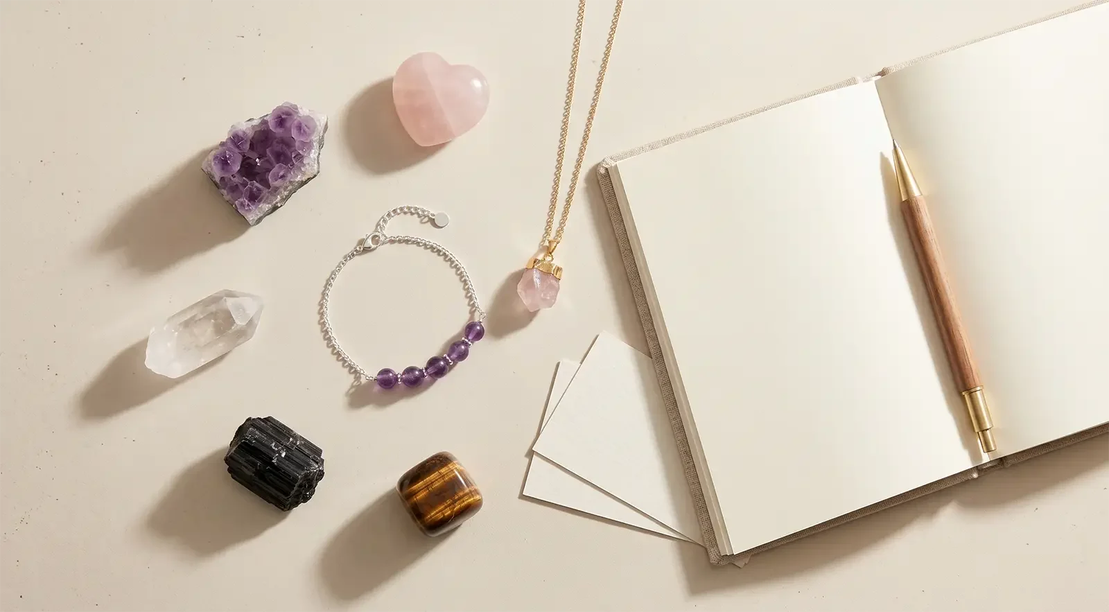 Gemstone bracelet, small pendant, notebook, pen, and blank cards arranged for choosing healing jewelry by one intention