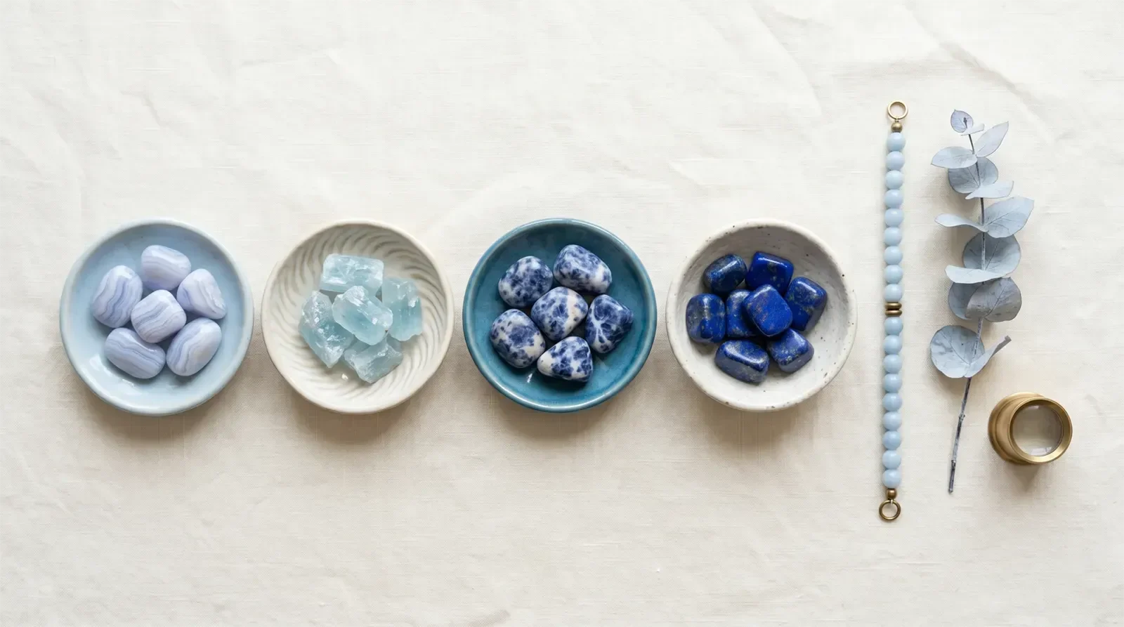 Đá aquamarine, mã não ren xanh, sodalite và lapis lazuli trong khay gốm cùng vòng tay xanh nhạt cho luân xa cổ họng
